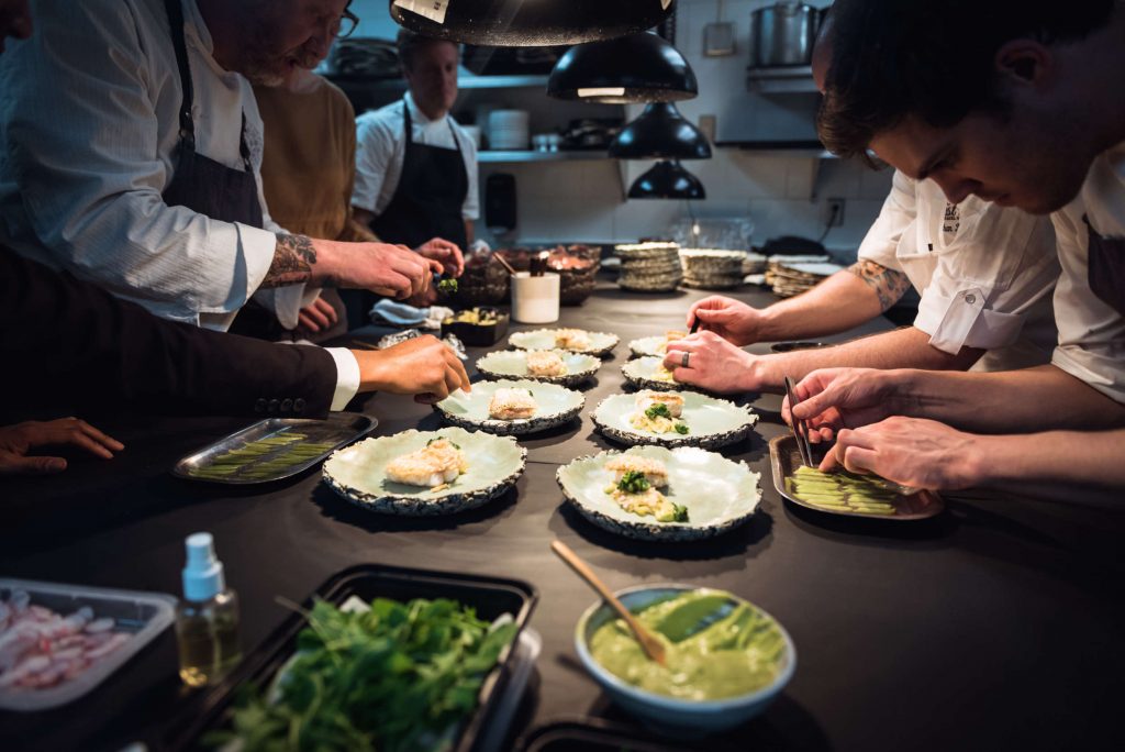 Group of Chefs Plating Dishes in the Aubergine Kitchen
